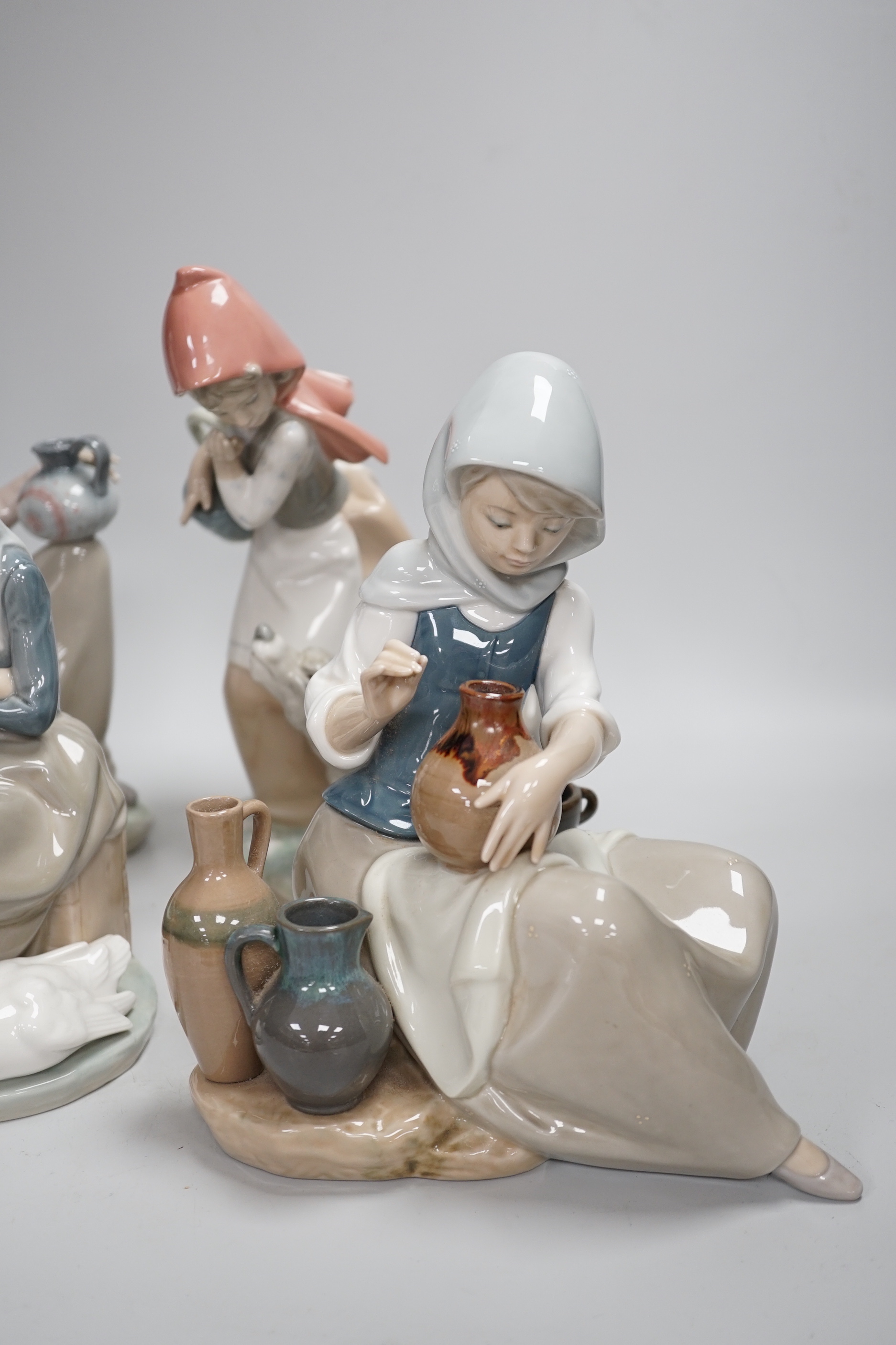 Four Lladro models, a girl potter, girl with ducks, mother and child with pottery and girl with a dog, highest 23.3cm